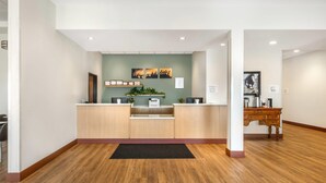 A reception area with a wooden reception desk, a green wall with artwork, and a wooden cabinet. - Radisson Hotel Pendleton Airport (Pendleton)