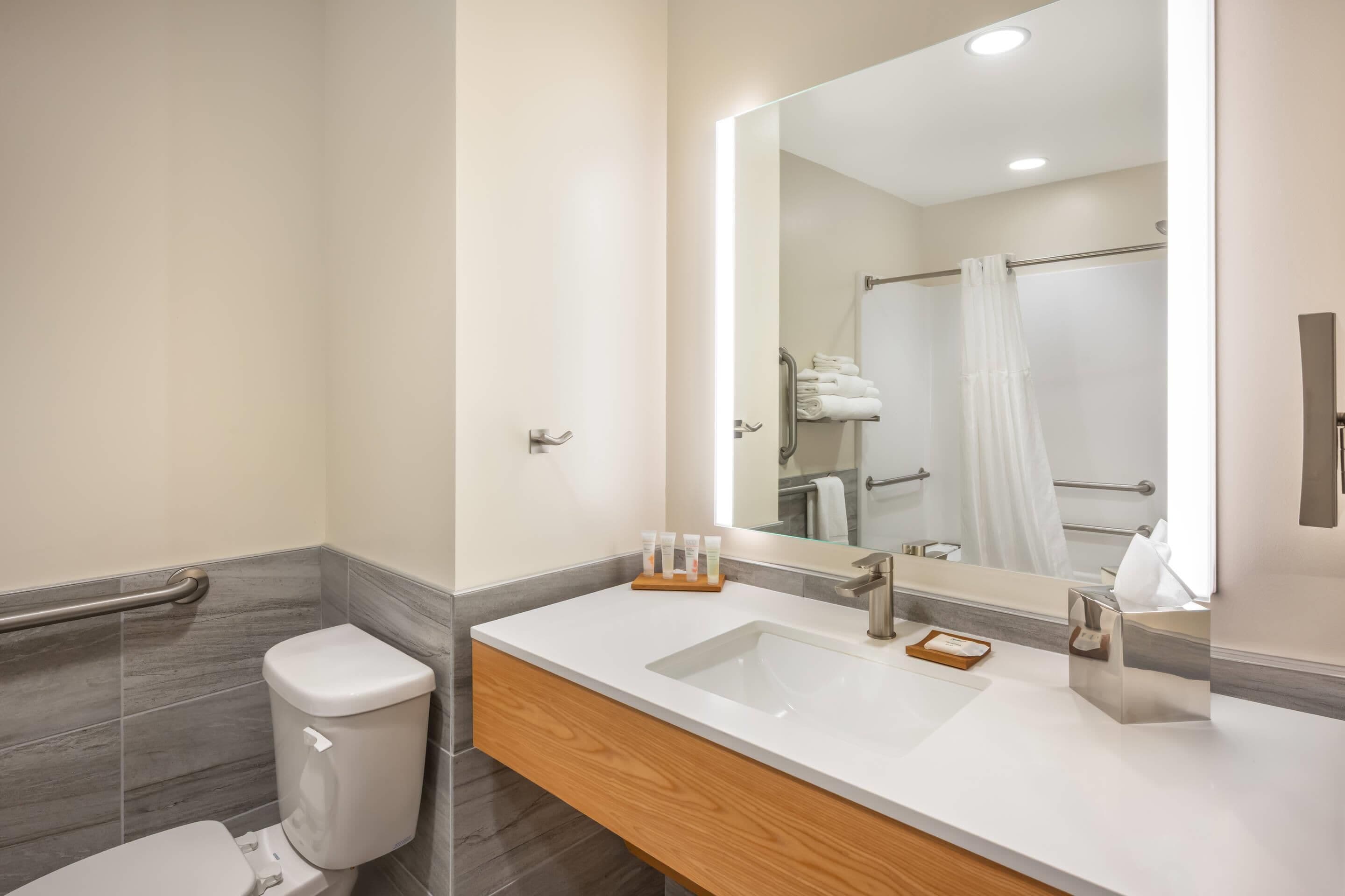 Une salle de bain moderne avec un lavabo blanc, un miroir et un espace douche.