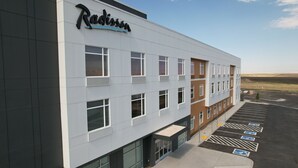 A Radisson hotel with a modern facade, multiple windows, and a parking lot with handicapped parking spaces. - Radisson Hotel Pendleton Airport (Pendleton)