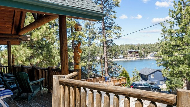 A wooden deck with chairs, overlooking a lake and houses.