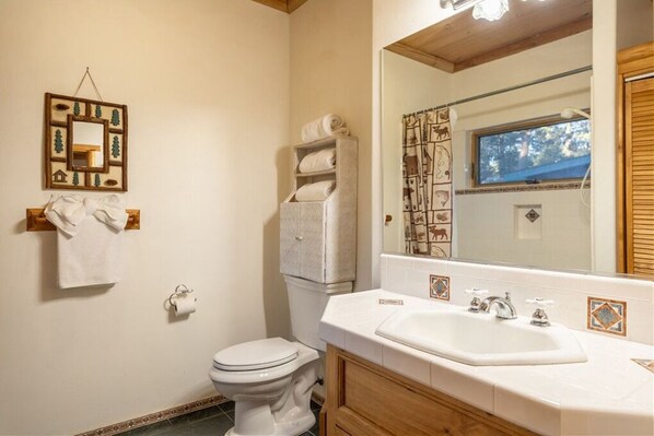 Un baño con inodoro, lavabo, espejo y toallero.