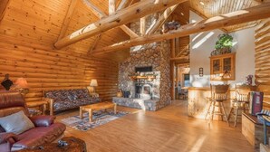 Ein Blockhaus-Interieur mit Kamin aus Stein, Holzmöbeln und einer gemütlichen Sitzecke.