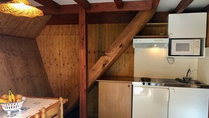 Een kleine keuken met houten balken, een magnetron, een fornuis en een spoelbak.