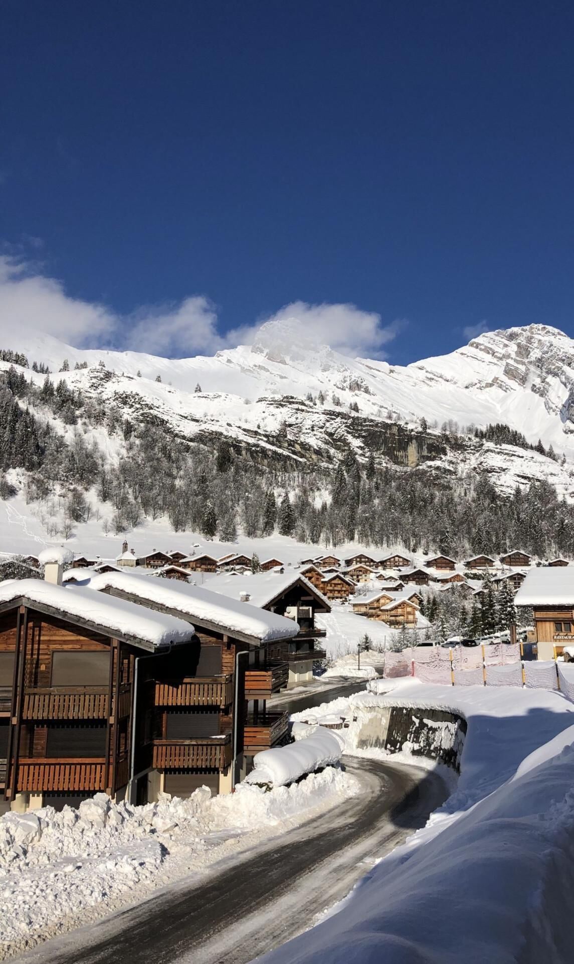 Ein verschneites Bergdorf mit Holzhäusern und blauem Himmel.