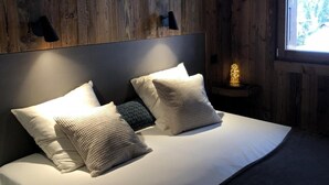 A wooden cabin-style bedroom with a bed, pillows, and a nightstand with a lamp. - Wifi, Ground floor, view mountain, terrace, parking, ski locker, 40m², Le Grand Bornand (Le Grand-Bornand)