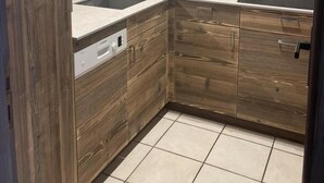 A compact kitchen with wooden cabinetry, a microwave, a sink, and a dishwasher. - Wifi, 50m from ski slopes, Ground floor, view mountain, terrace, fireplace or stove, parking, 55m² (Le Grand-Bornand)