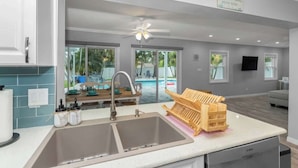 Cocina con un lavaplatos doble, un escurreplatos de madera y un lavavajillas Bosch.