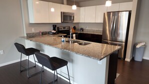 Uma cozinha moderna com uma ilha central, eletrodomésticos de aço inoxidável e banquetas.