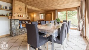 A spacious dining area with a long table, multiple chairs, and a stone fireplace.
