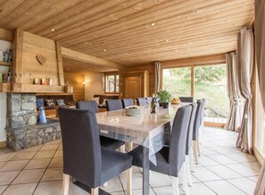 A spacious dining area with a long table, multiple chairs, and a stone fireplace.