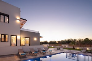 Relax by the pool surrounded by lounge chairs and a serene garden.