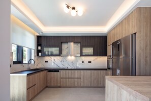 Een moderne keuken met houten kastjes, een roestvrijstalen koelkast en een marmeren achterwand.