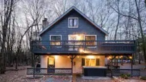 A two-story house with a balcony, a covered porch, and a small front yard. - Zen Escape : Game Room : Hot Tub (Albrightsville)