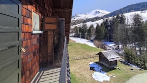 A wooden cabin with a balcony overlooking a snowy mountain landscape.