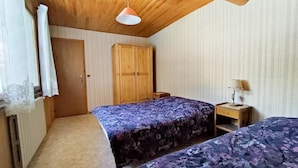 A bedroom with two beds, wooden wardrobe, and a ceiling fan.