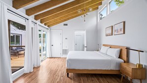 A bedroom with a wooden floor, a bed with white bedding, a nightstand, and a ceiling fan. - Casa Lily*Near Sandestin*PrivateHeatedPool*Bikes* (Miramar Beach)
