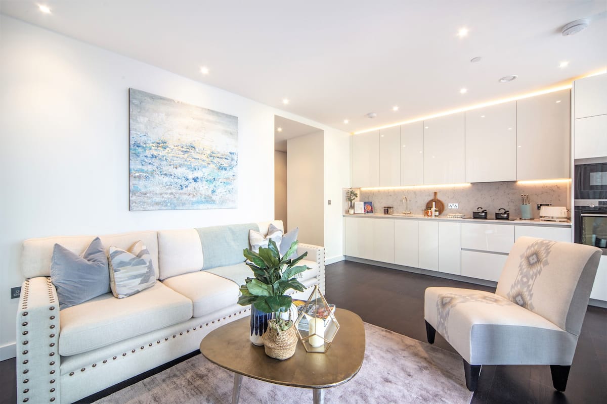 Un salon moderne avec un canapé, un fauteuil, une table basse et un tableau accroché au mur.