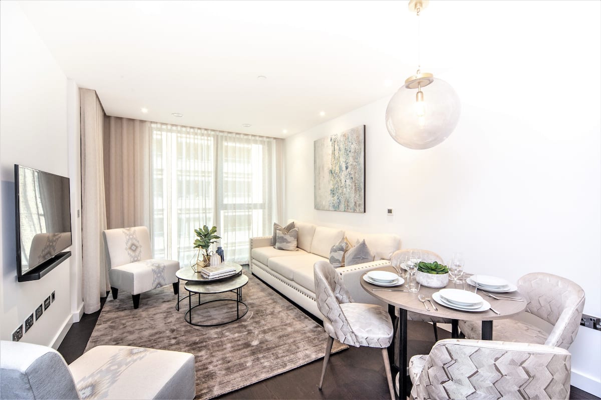 Un salon moderne comprenant un canapé, des fauteuils, une table basse et une table à manger pour quatre personnes.