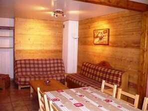 A cozy room with wooden walls, a sofa, a table, and a bed.
