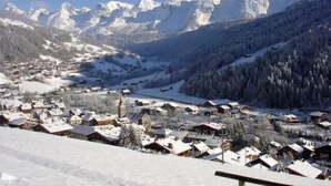 Un pueblo cubierto de nieve con casas de madera tradicionales, una iglesia y montañas al fondo.