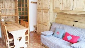 Una habitación con una mesa de madera, un sofá con almohadones y un armario.