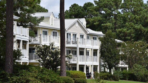 A multi-story hotel with balconies, surrounded by lush greenery and trees. - 1401m 1 Bedroom Condo by Redawning (Calabash)