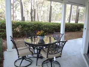 Relax in a serene outdoor setting with a round table and comfortable seating for four, surrounded by lush greenery.