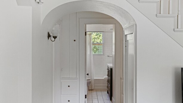 Un pasillo con una puerta blanca que da a un baño.