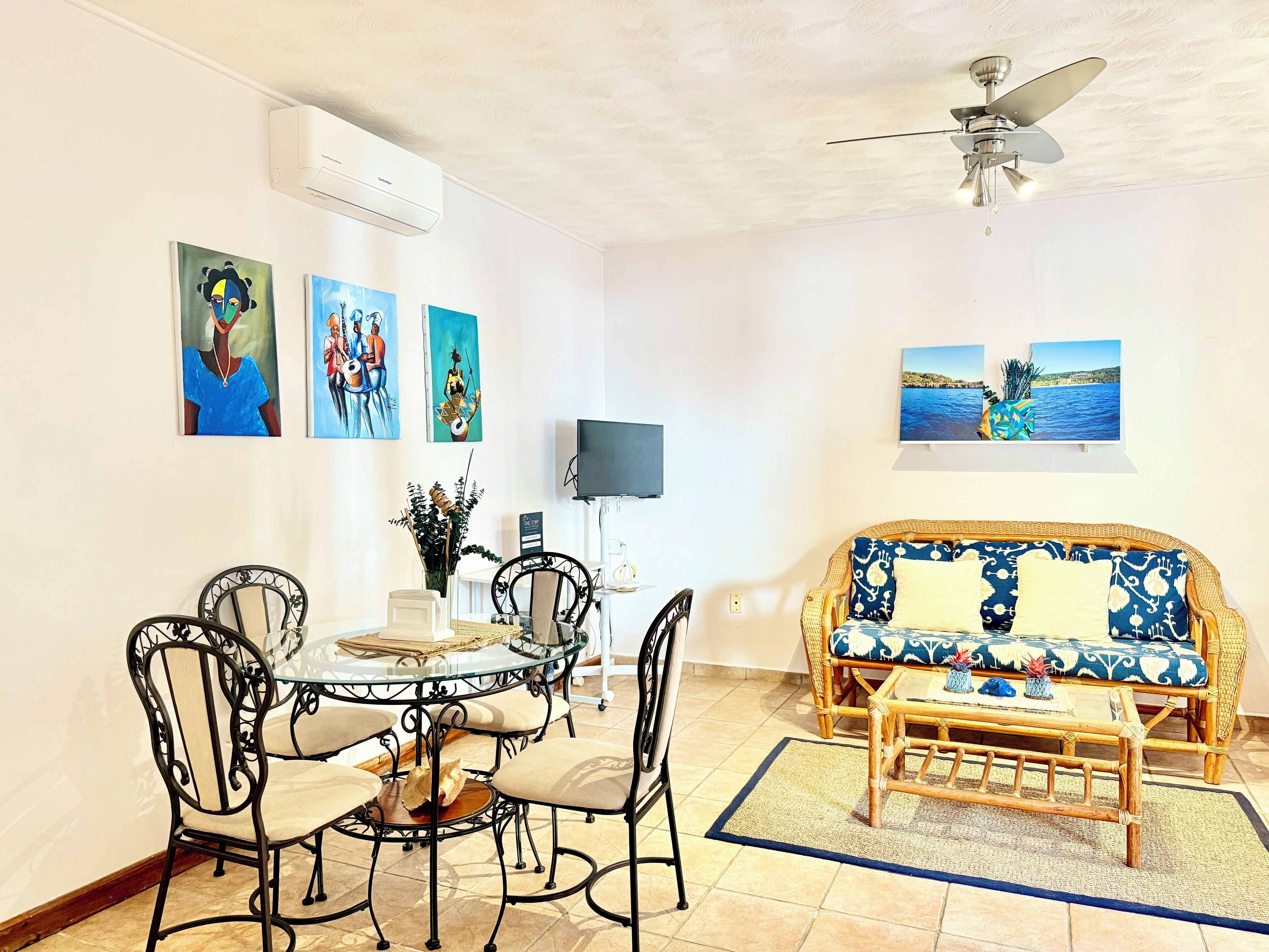 A dining area with a round table and chairs, a sofa, and artwork on the walls.