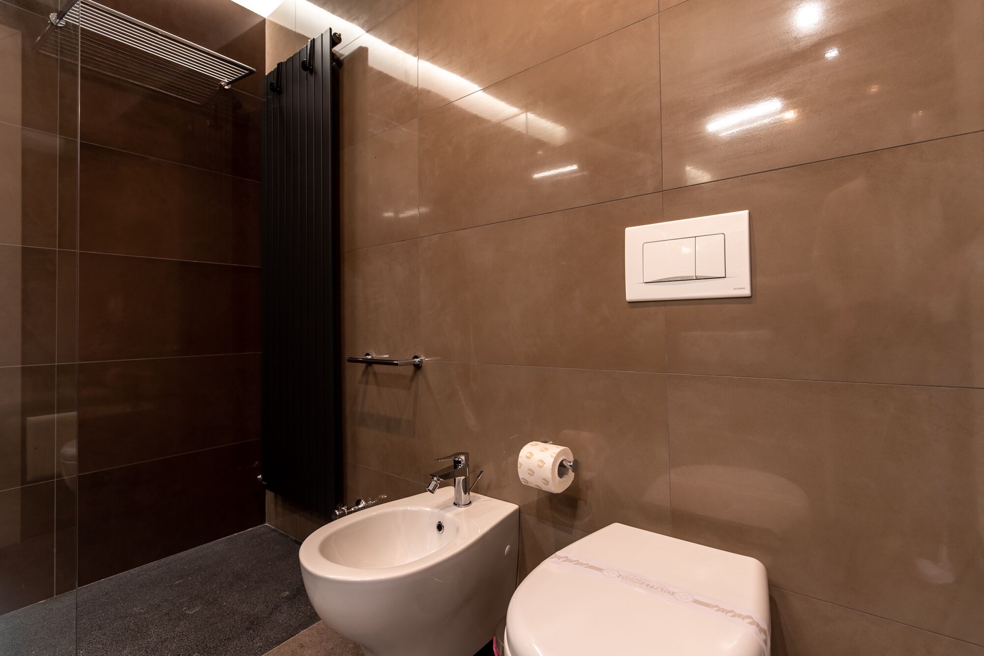Une salle de bain moderne équipée d’un bidet, de toilettes et d’un porte-serviettes.