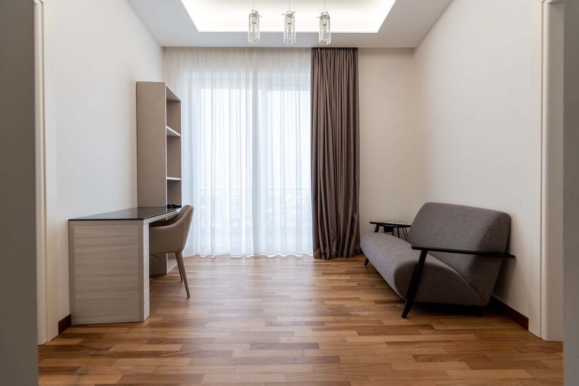 Ein kleines Zimmer mit Schreibtisch, Stuhl und Schlafsofa.
