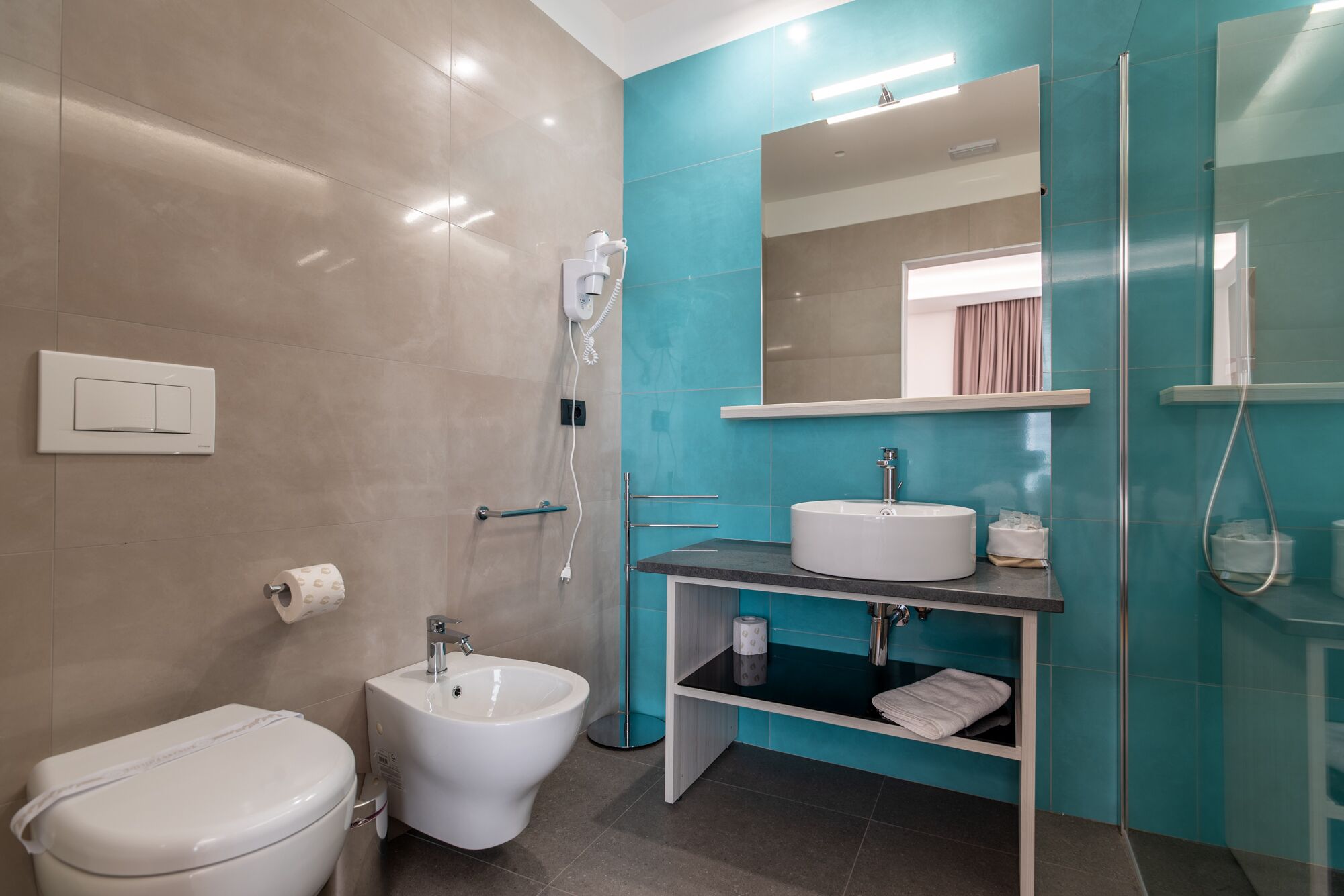 A modern bathroom with a bidet, a toilet, a sink, and a mirror.