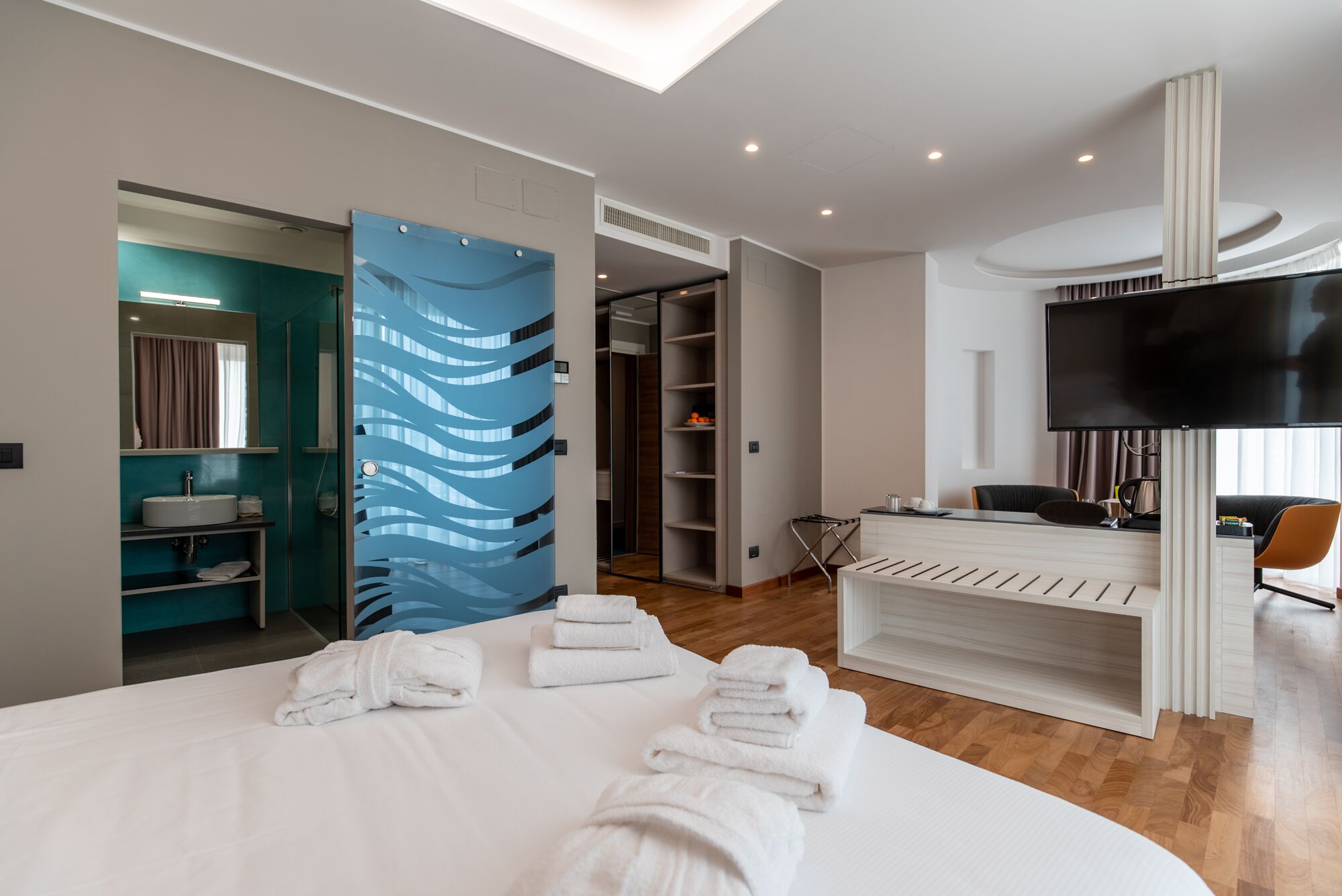 Une chambre d’hôtel moderne équipée d’un grand lit, d’une télévision, d’un bureau et d’un dressing.