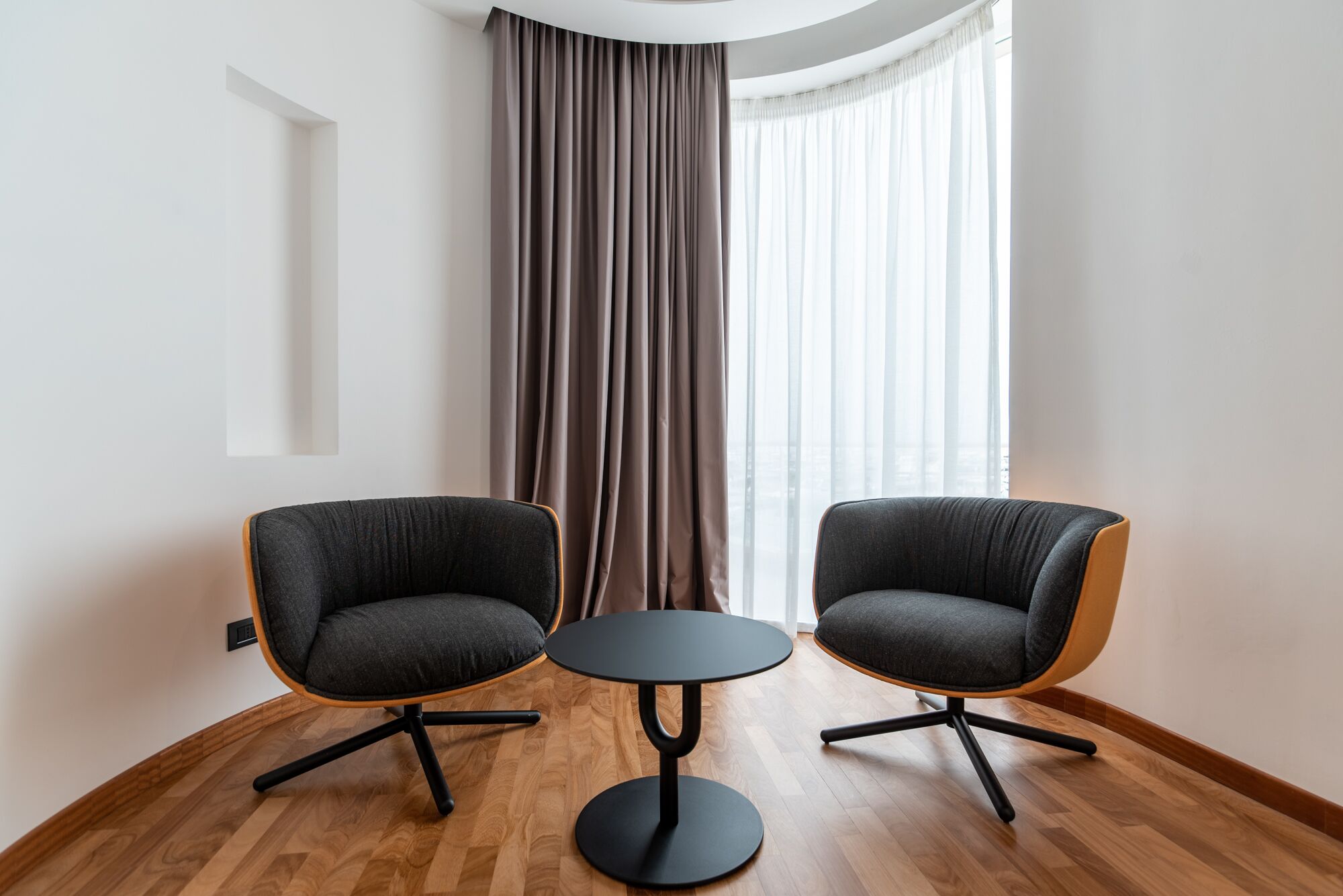 A modern room with two grey armchairs and a small round table.