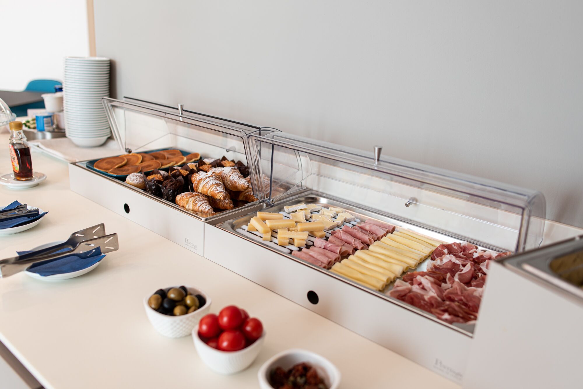 Un bufé con diversas opciones de comida, incluyendo pasteles, quesos, carnes y aceitunas.