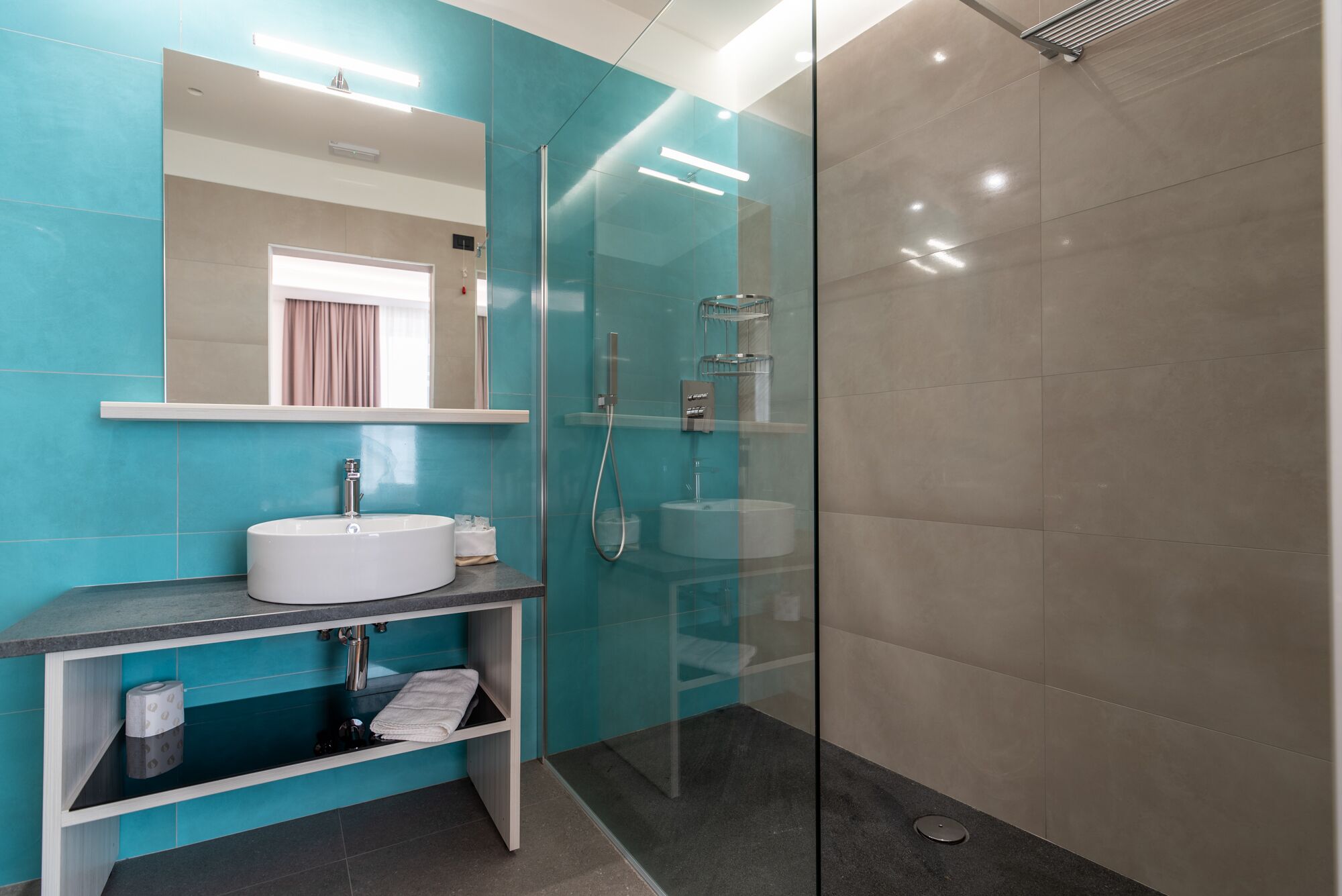 A modern bathroom with a glass shower enclosure, a white sink, and a mirror above it.