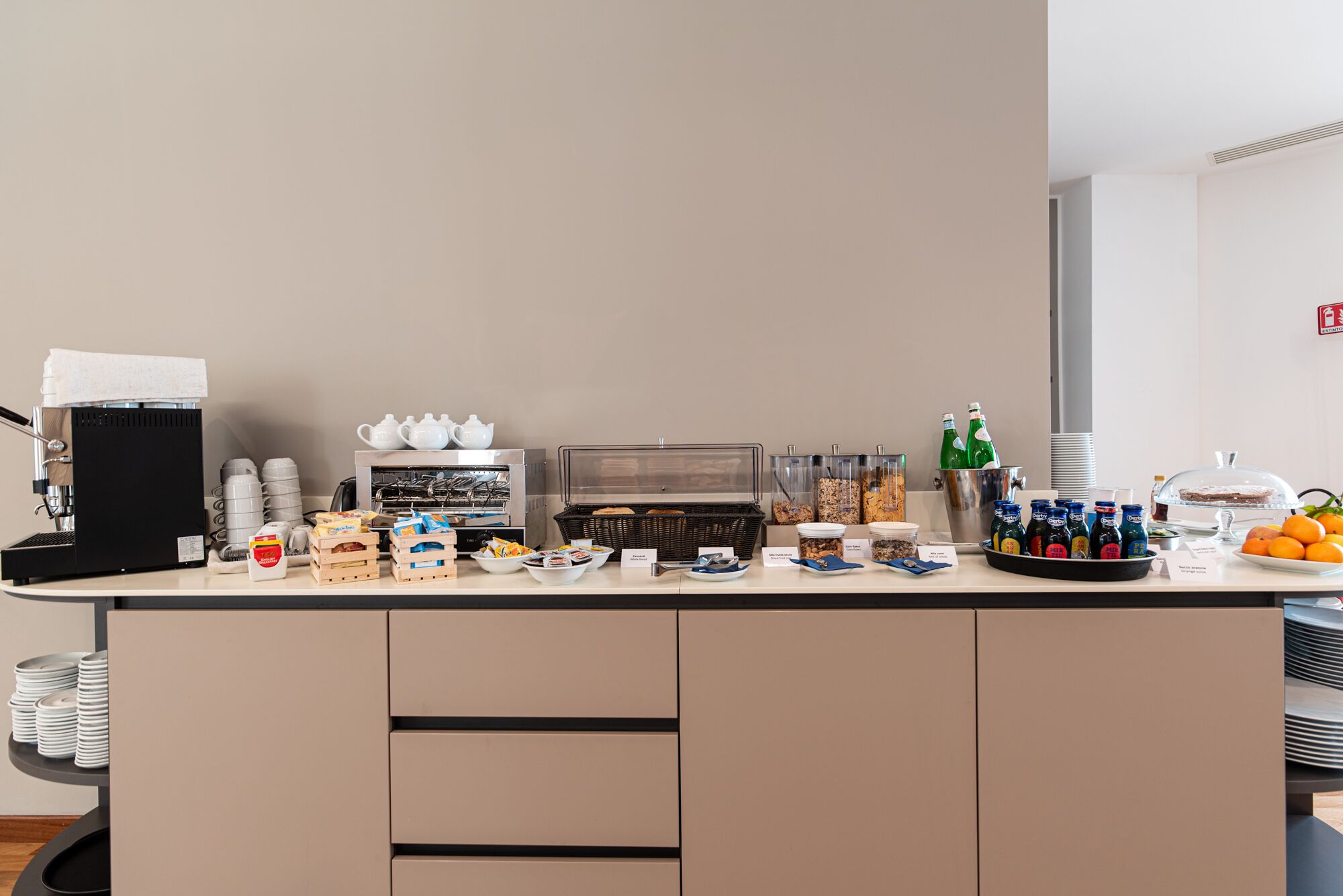 A breakfast bar with coffee machines, tea pots, and various food and drink containers.