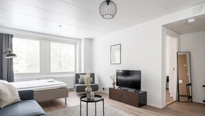 Una sala de estar moderna con un sofá, una mesa de centro, un televisor y un amplio ventanal.