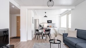 Una sala de estar moderna con un sofá gris, un televisor y una zona de comedor con una mesa y sillas.