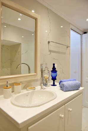 A bathroom with a white sink, a mirror, a towel rack, and a blue decorative item.
