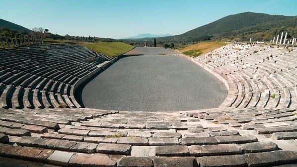 An ancient amphitheater with stone seating and a central stage.