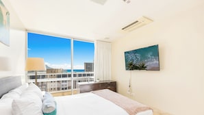 Une chambre d’hôtel avec un grand lit, une vue sur la ville et un téléviseur fixé au mur.