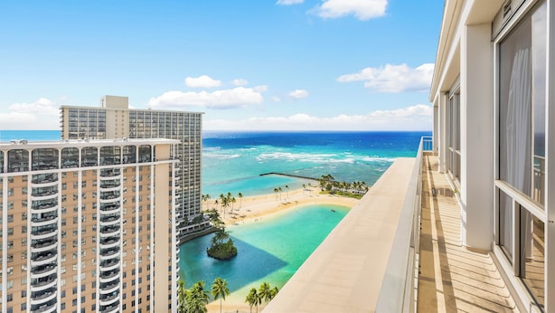 Un hôtel de grande hauteur doté d’un balcon donnant sur une plage et l’océan.