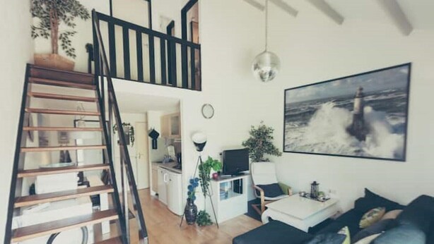 Un salon moderne avec un escalier, un coin repas et une cuisine.