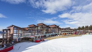 Ein modernes Skiresort-Gebäude mit mehreren Ebenen und Balkonen, umgeben von Schnee.