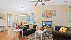 A living room with two sofas, a TV, and a ceiling fan.