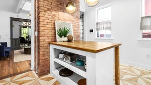 A kitchen with a brick wall, wooden countertop, and hanging pendant lights. - Modern Midtown Getaway - Luxury and Chic (Atlanta)