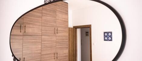 Una habitación con un armario de madera, un espejo y un pequeño adorno en la pared.