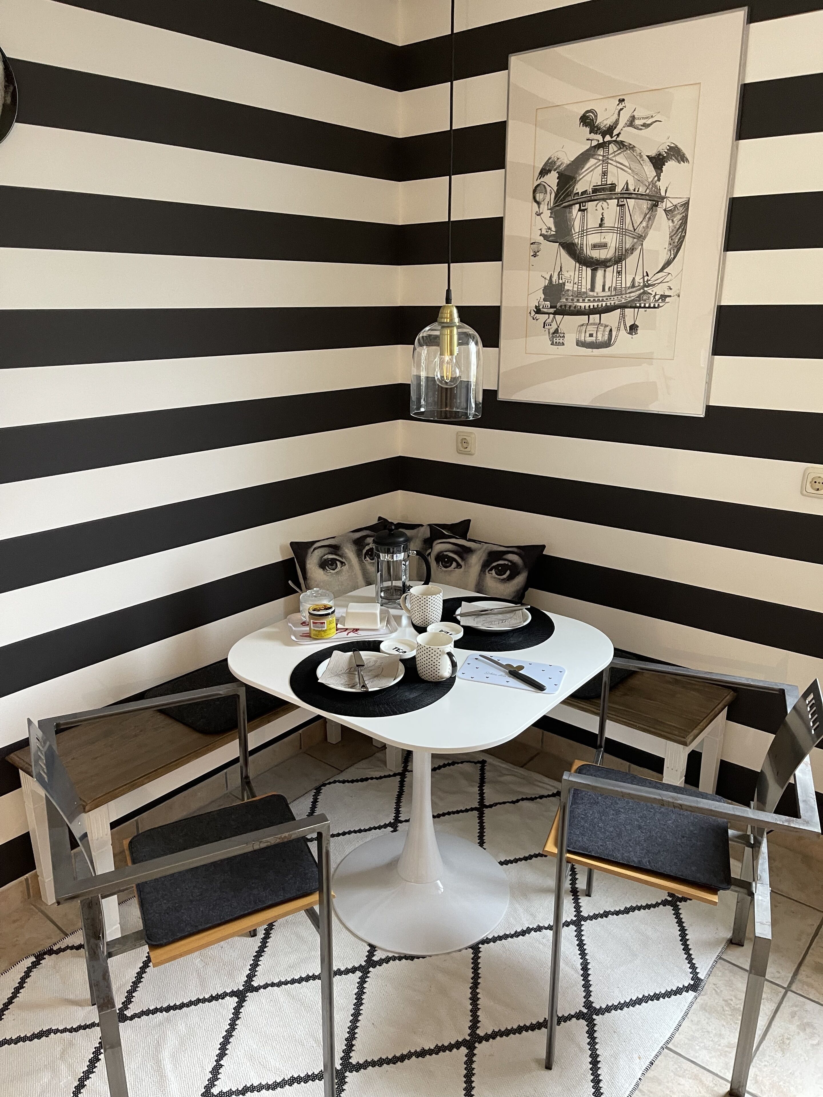 Ein Essbereich mit einer schwarz-weiß gestreiften Wand, einem runden Tisch mit Stühlen und einem Globus als Wandkunst.