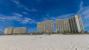 A beachfront hotel with multiple high-rise buildings, sandy beach, and clear blue sky. - Beach Club D0302- Direct Gulf View - Beach - Pool - WIFI (Gulf Shores)